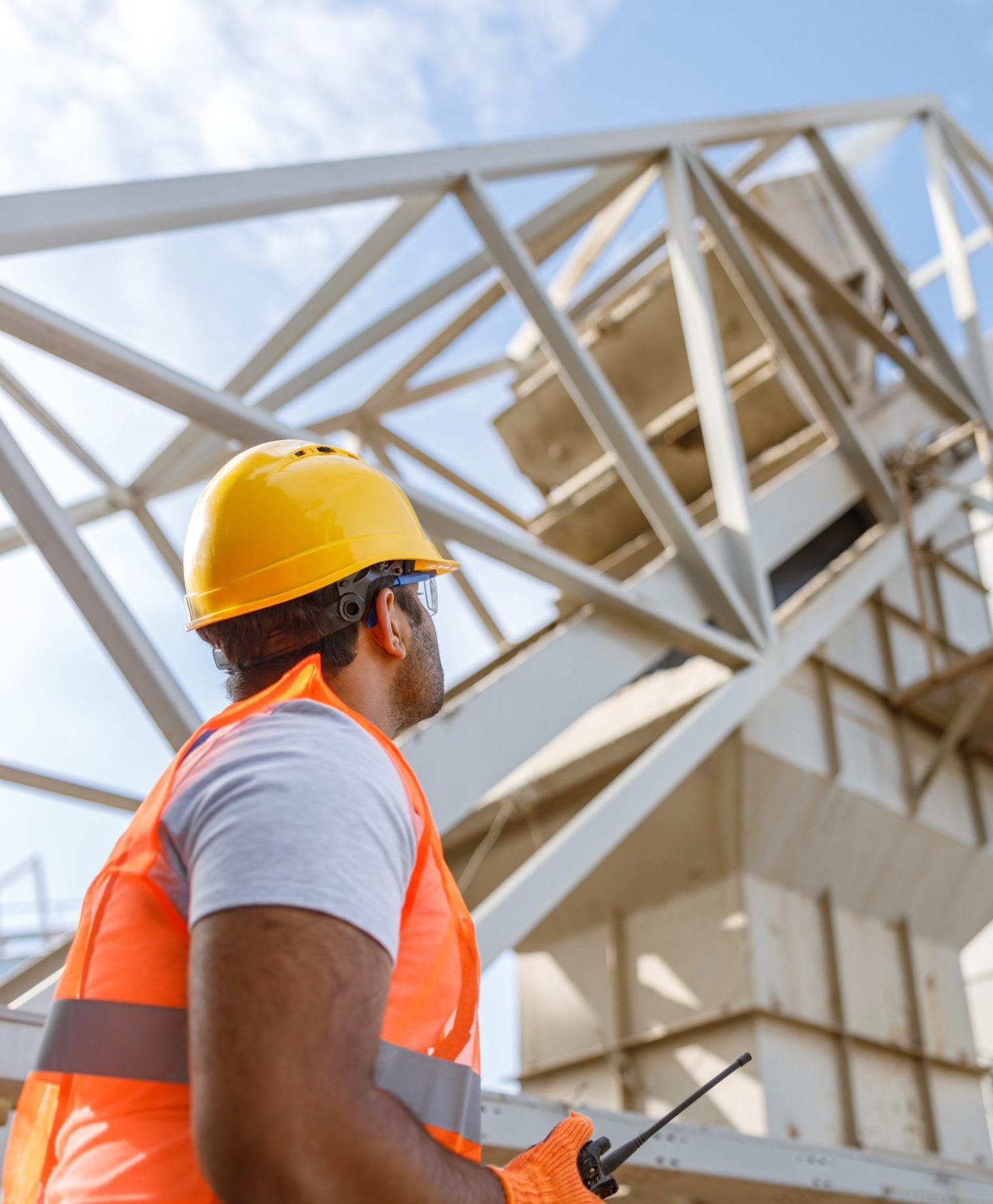 Low angle view of industrial worker in protective uniform, observing working process at plant for construction industry production